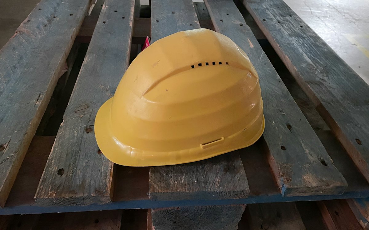 Capacete de segurança amarelo apoiado sobre tábuas de madeira