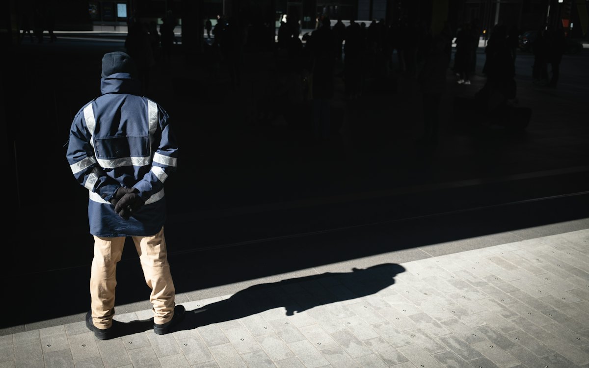 Vigilante de costas em uma calçada à noite