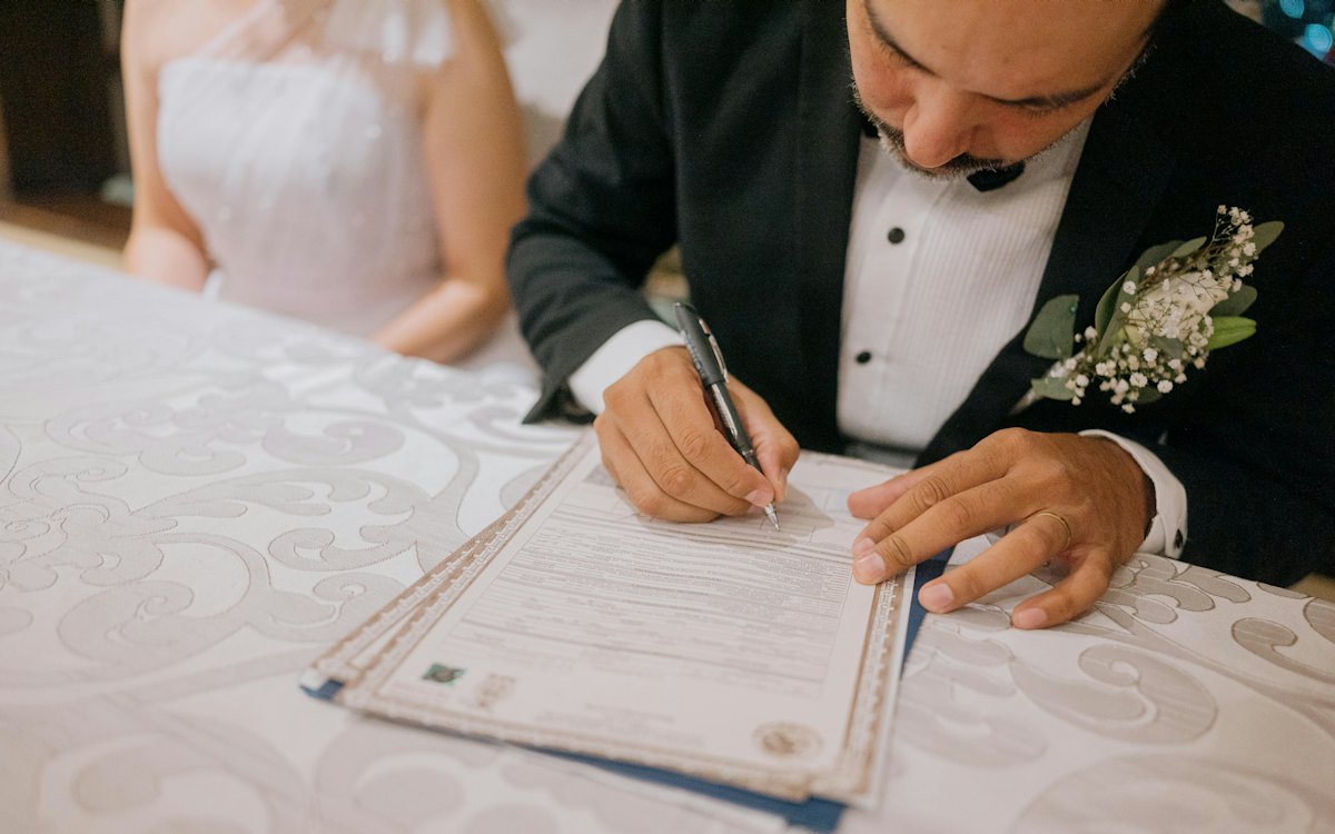 Noivo assinando o livro de registro durante o casamento civil