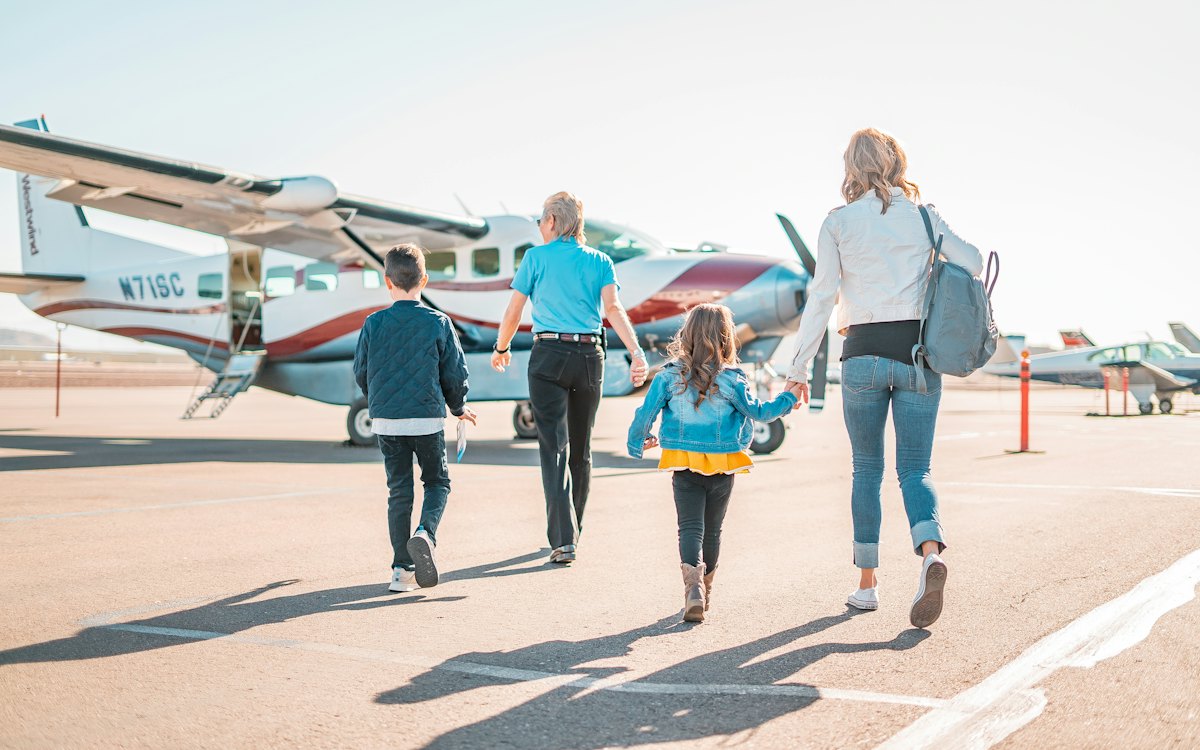Adultos e criança caminhando até um avião na pista