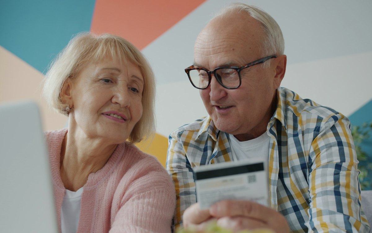 Casal de idosos conferindo um cartão bancário
