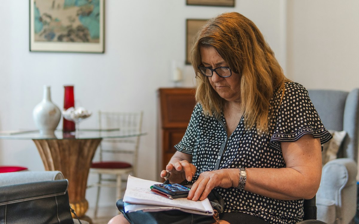 Mulher conferindo contas com calculadora sobre a mesa