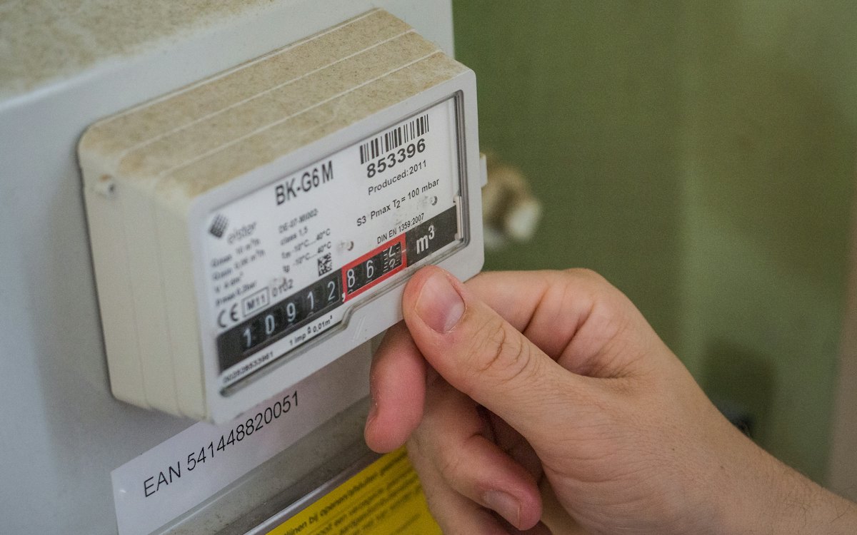 Mão apontando para o visor de um medidor de energia