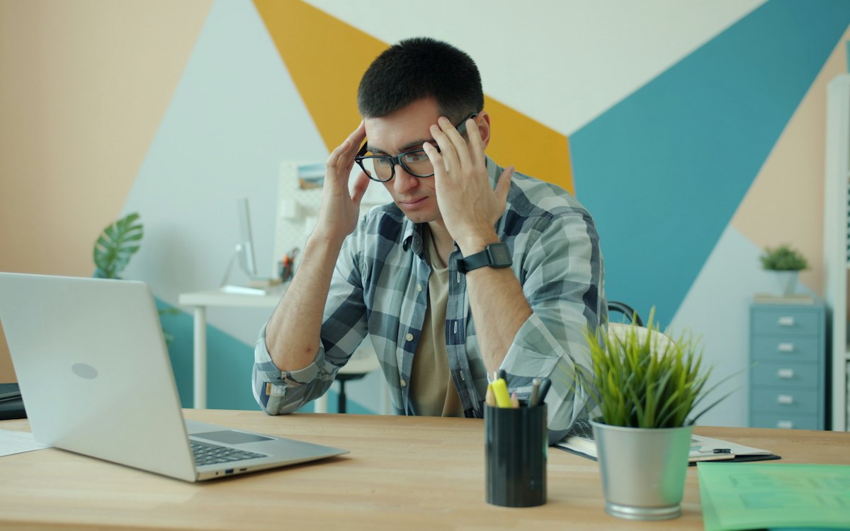 Homem estressado com as mãos na cabeça diante do notebook