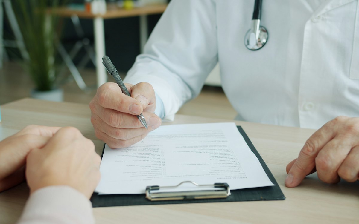 Médico preenchendo um documento em uma prancheta