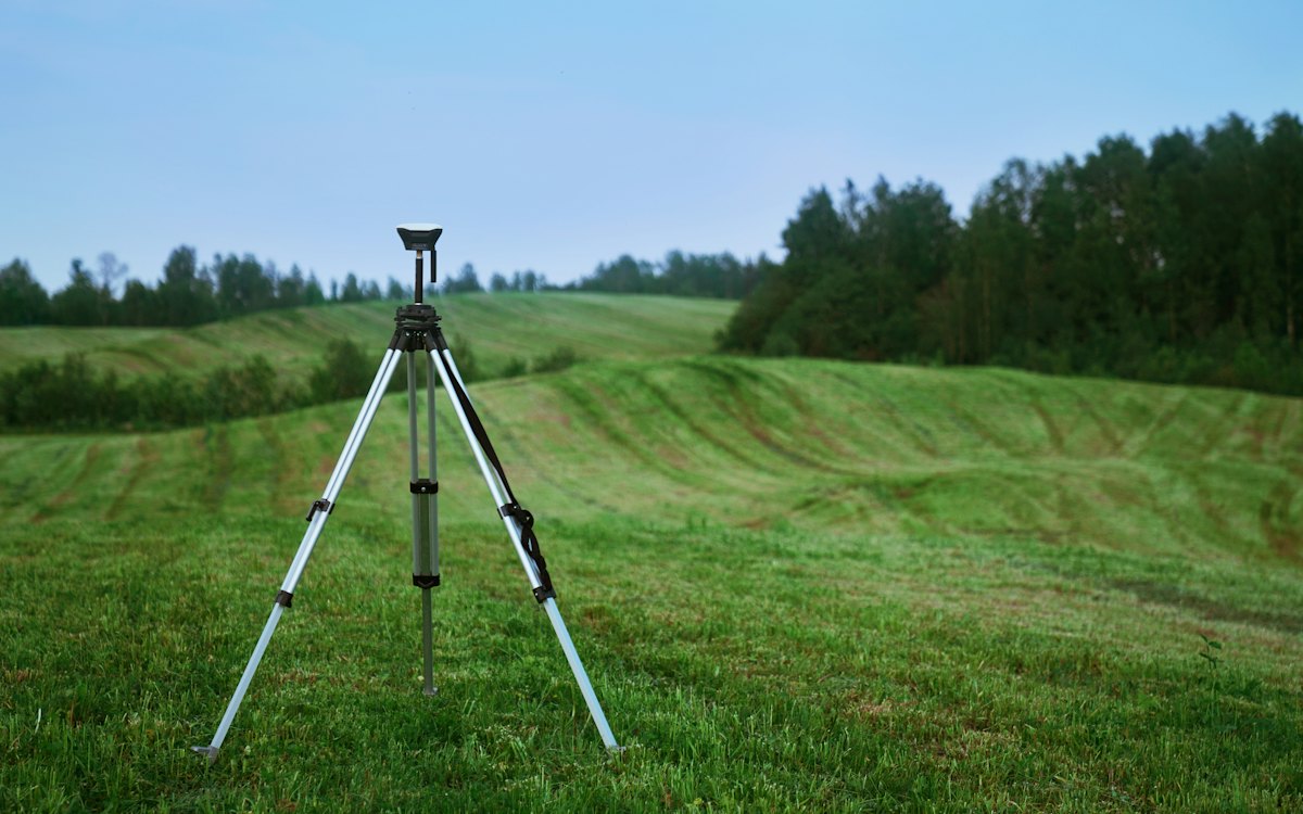 Equipamento de topografia sobre tripé em um terreno gramado