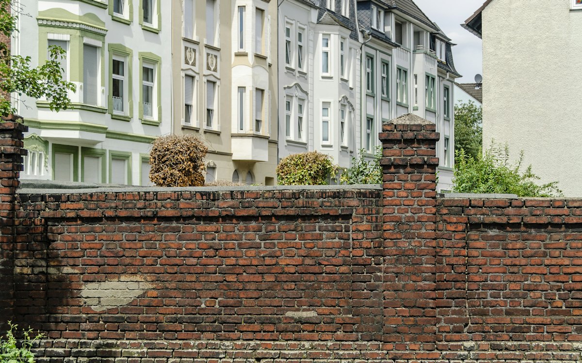 Muro de tijolos dividindo casas vizinhas em uma rua residencial