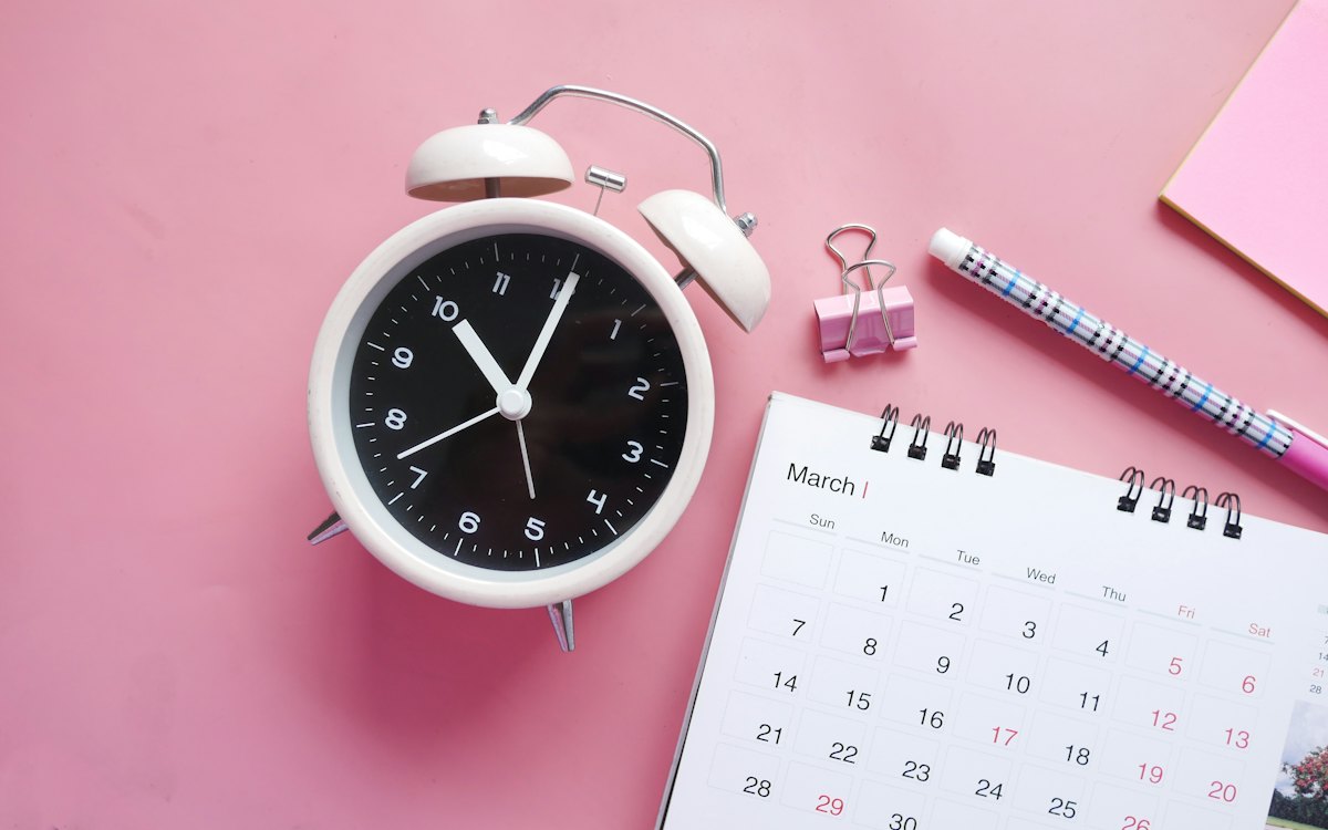 Relógio despertador ao lado de um calendário