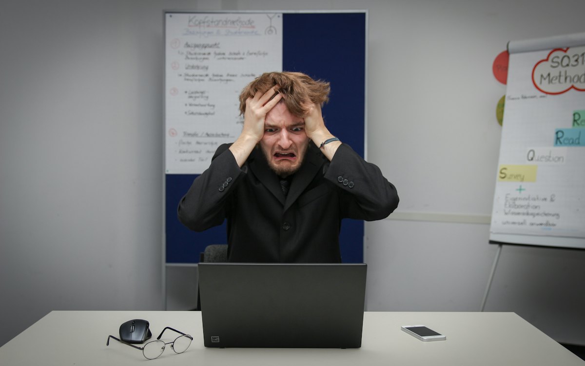 Homem com as mãos na cabeça em frente ao computador