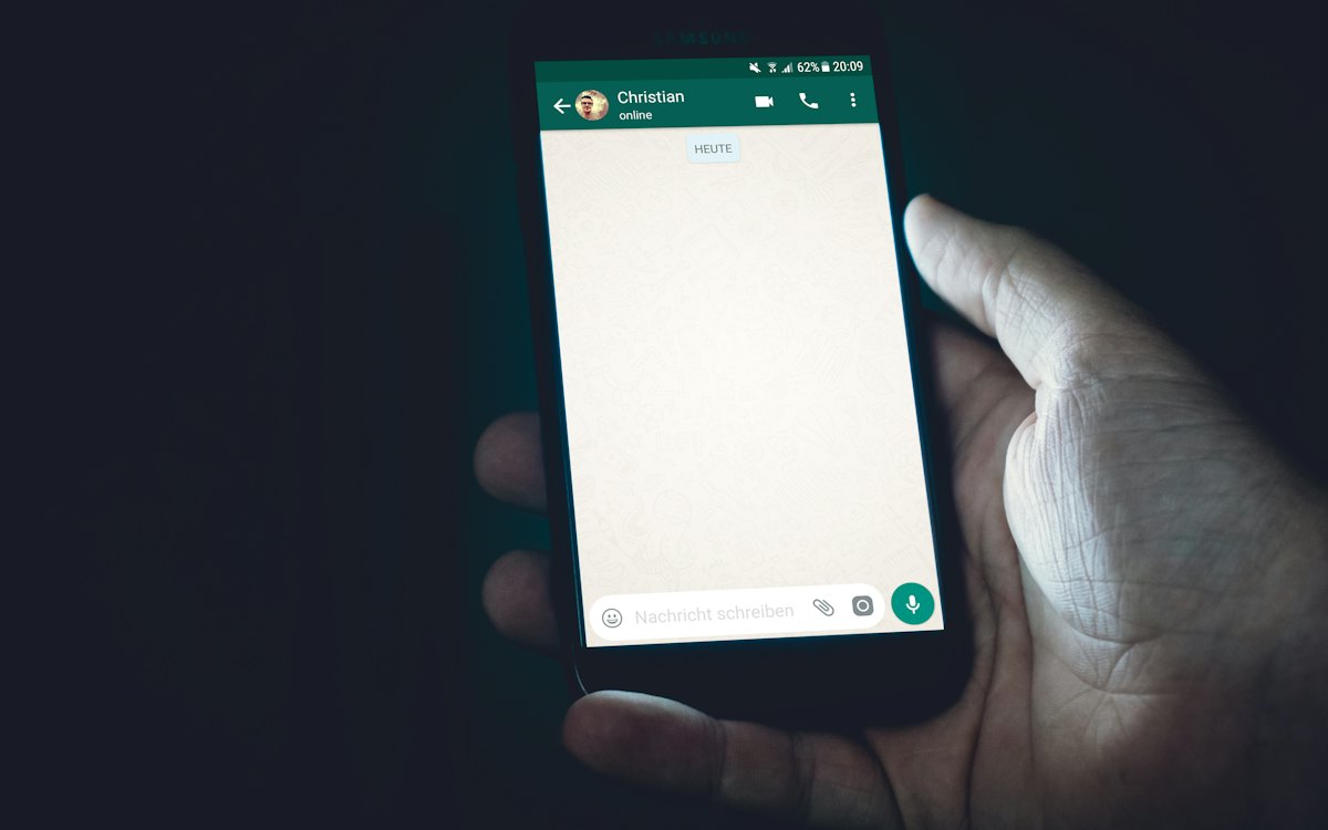 Mão segurando celular com aplicativo de mensagens aberto