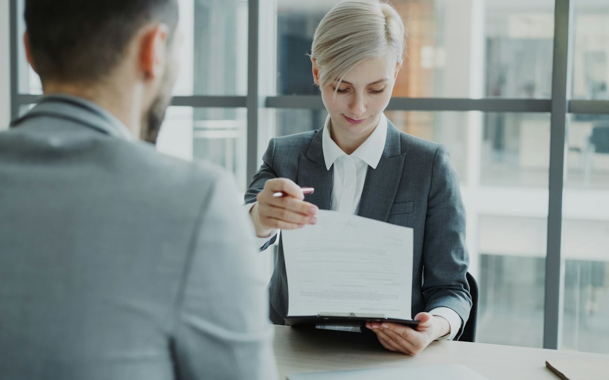 Profissional de recursos humanos segurando um documento em reunião