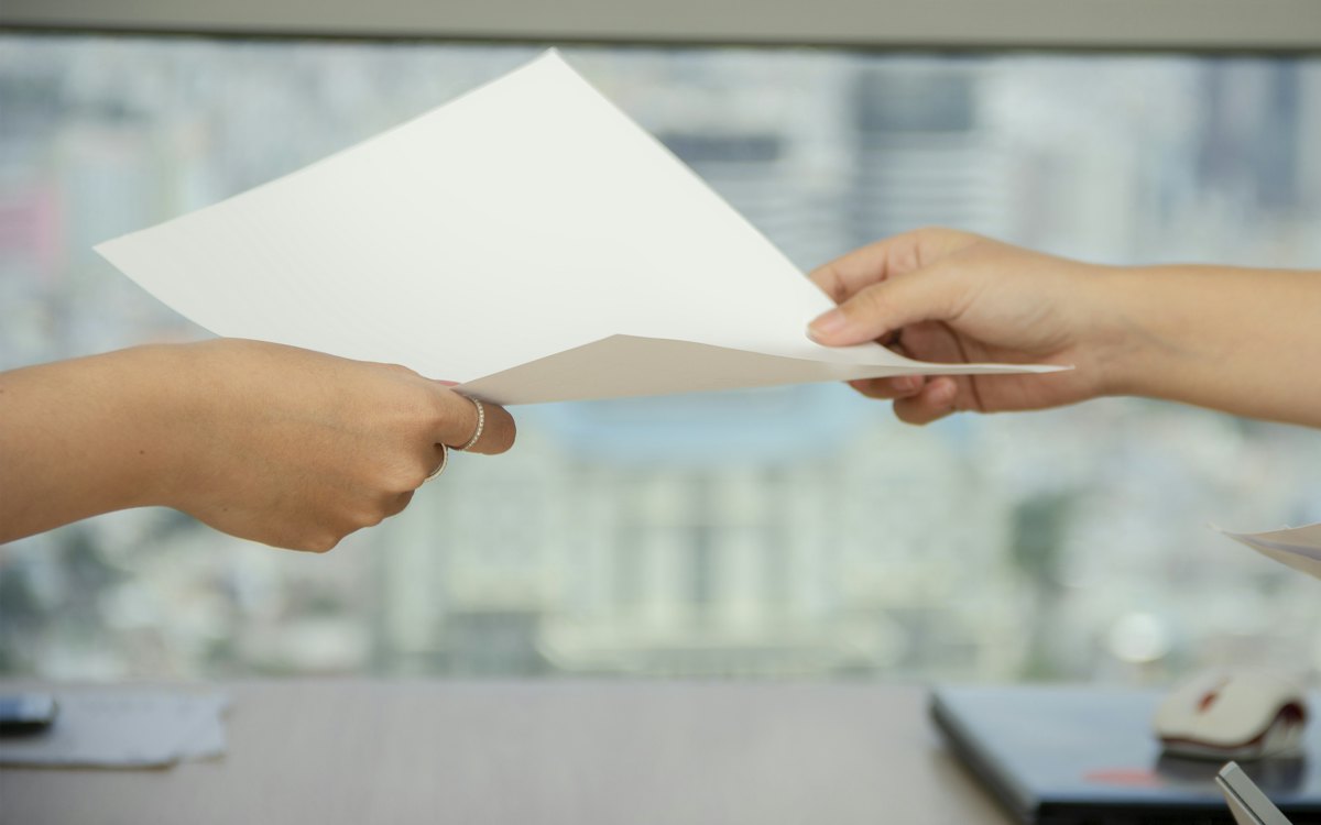 Mãos entregando uma folha de papel a outra pessoa
