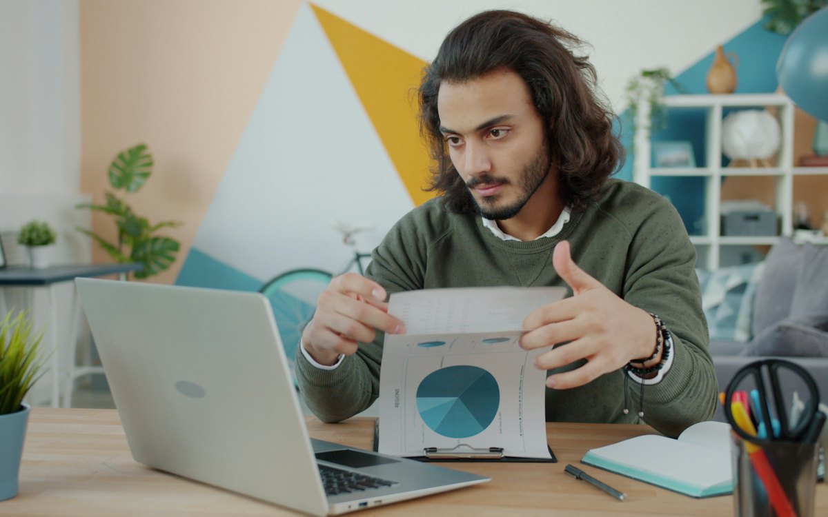 Homem trabalhando no notebook e analisando um relatório
