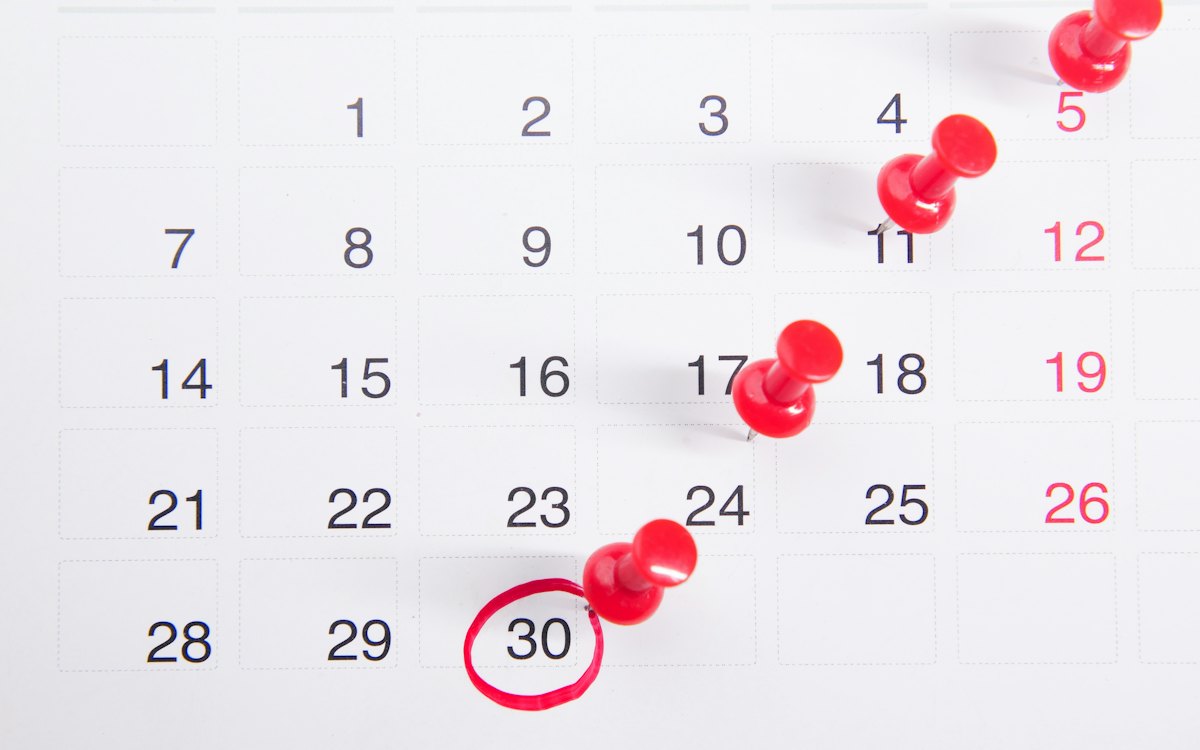 Calendário com datas marcadas por alfinetes vermelhos