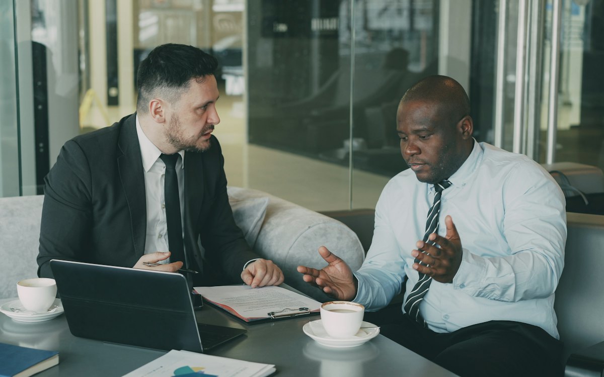 Dois empresários conversando seriamente diante de um notebook