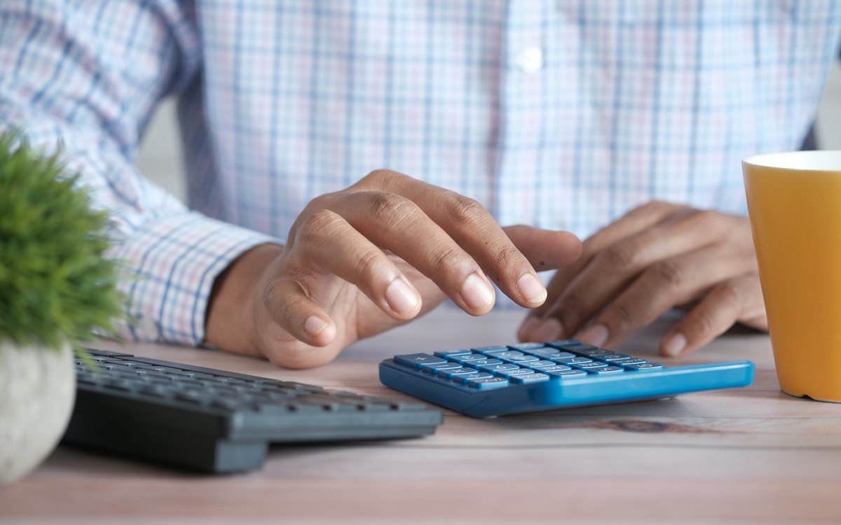 Pessoa fazendo contas em uma calculadora azul