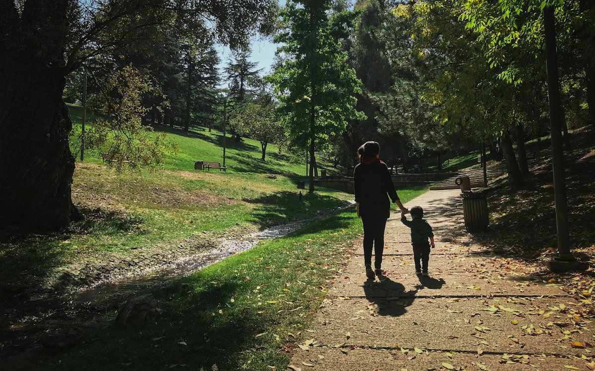 Adulto e criança caminhando de mãos dadas em um parque