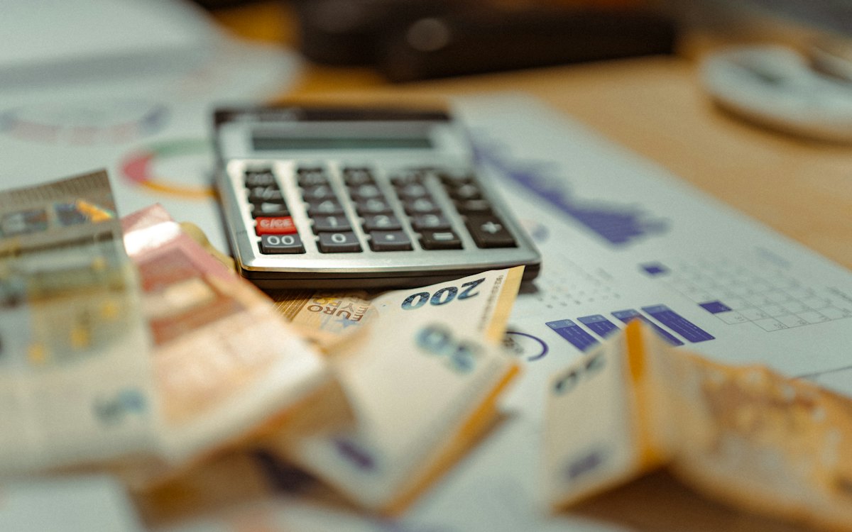 Calculadora e cédulas de dinheiro sobre papéis com gráficos