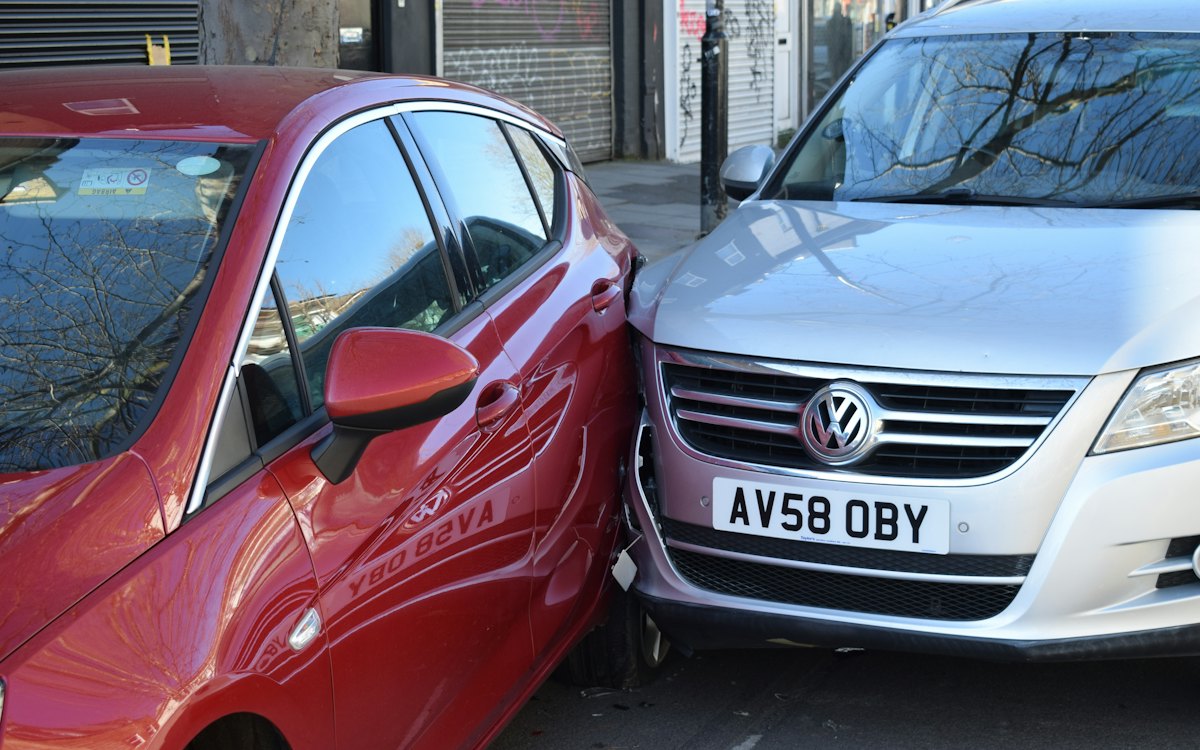 Dois carros batidos lado a lado na rua
