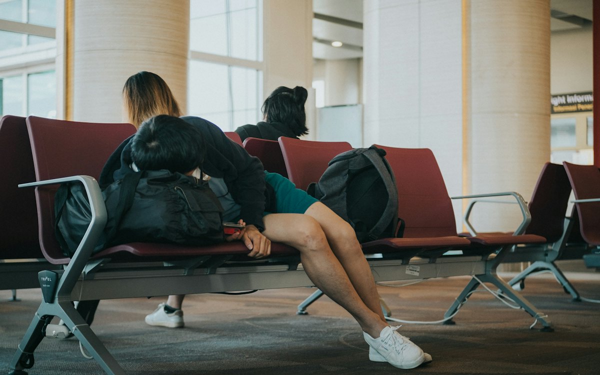 Passageiros cansados esperando deitados nas cadeiras do aeroporto